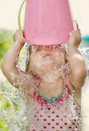 Child playing with a pink bucket, splashing water outdoors - Learn to Swim - Overcome Water Phobia Singapore
