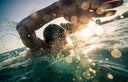 Person swimming at Open Water with sunlight creating a bokeh effect - Open Water Swimming at Sentosa Singapore