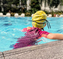 Young Child wearing a yellow swim cap and pink swimsuit in a pool - Condominium Swimming Lessons Singapore