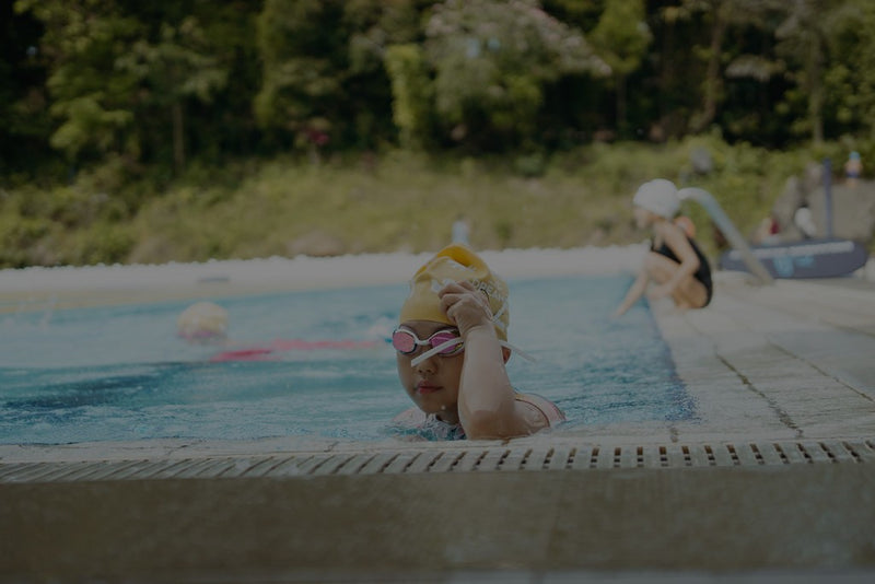 A girl resting at poolside after swim meet - Dreamers Swim Meet Singapore