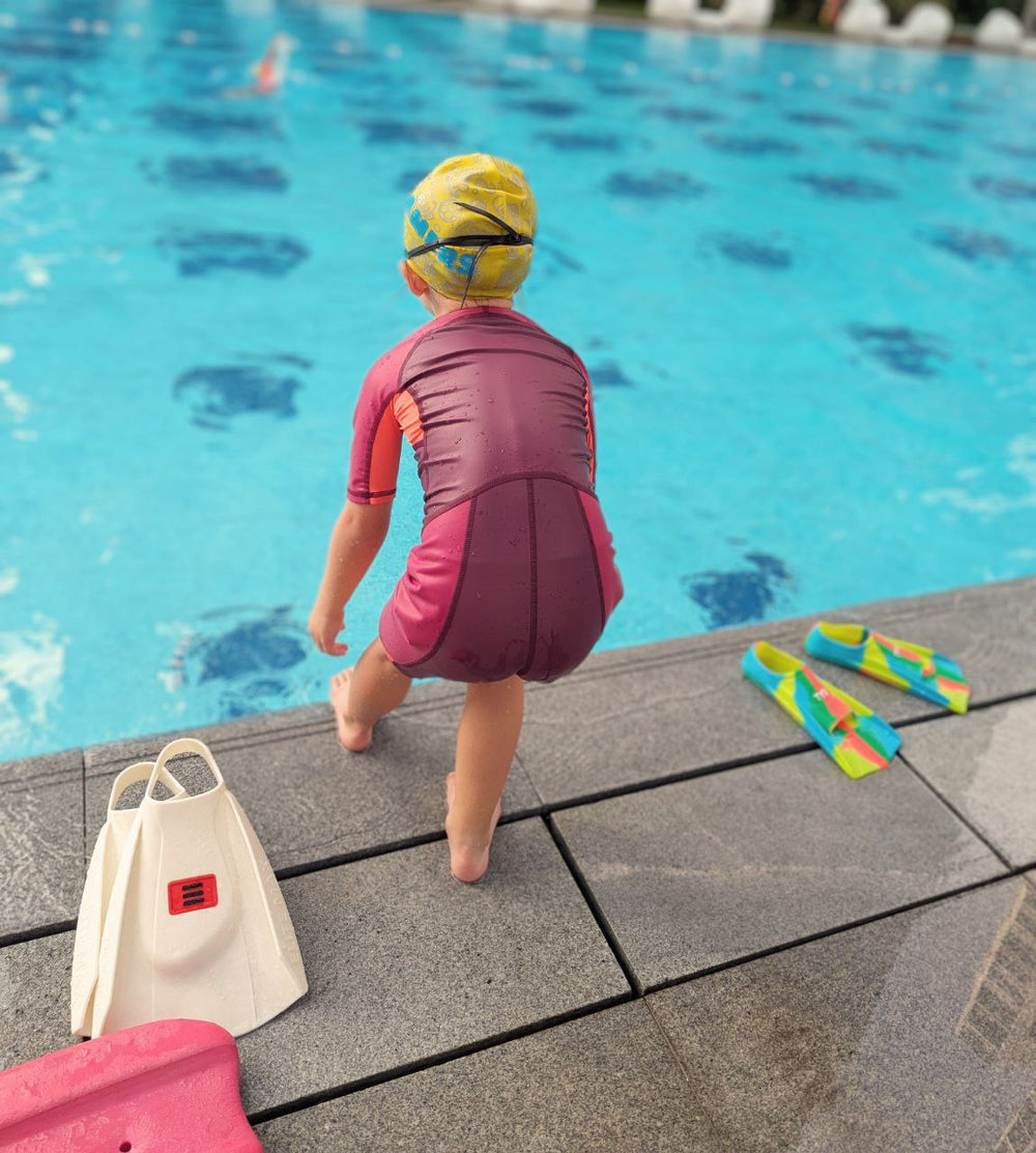 Child preparing to plunge by the pool side during a Dreamers swimming lesson