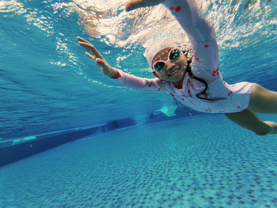 Child swimming underwater with goggles at a condo pool in Singapore