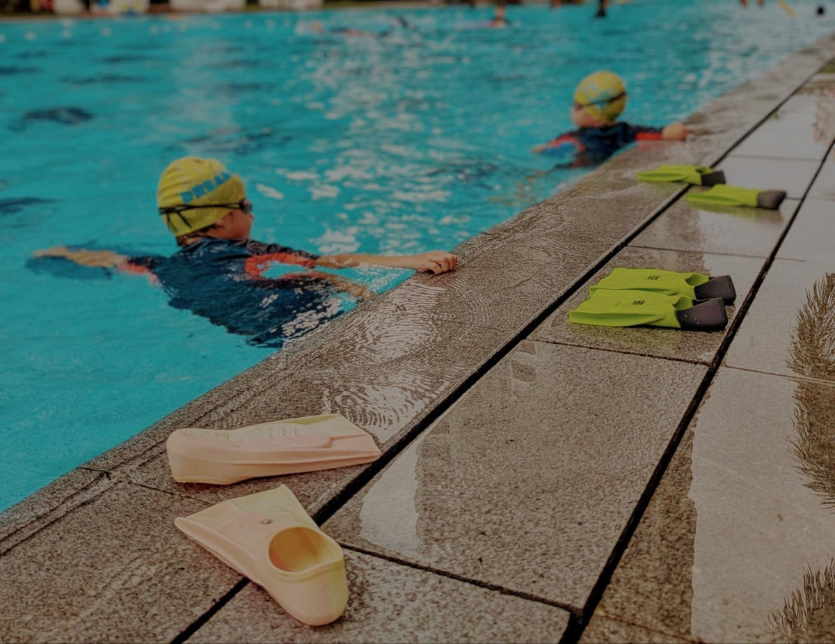 Children swimming in a pool with fins and goggles, Dreamers Swim Academy Singapore