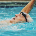 Elderly swimming in a pool with water droplets around - Swimming Lessons for Seniors SIngapore