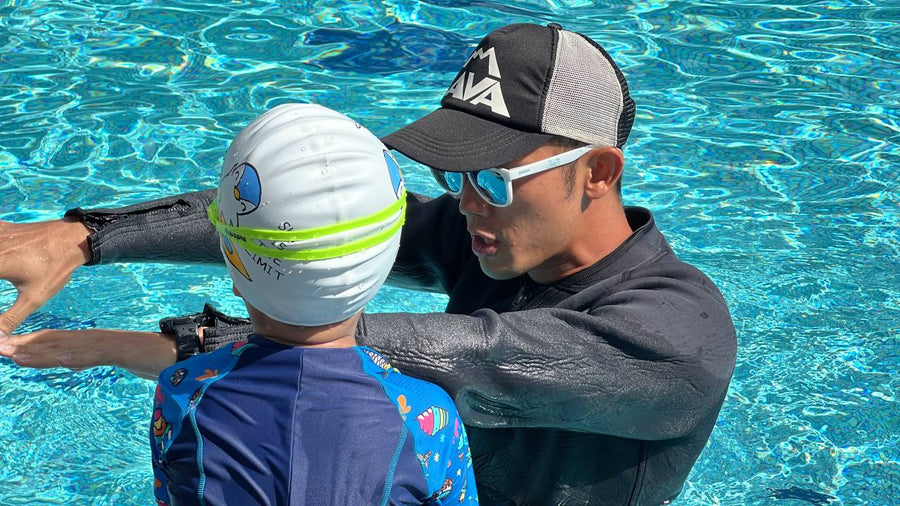 Dreamers coach correcting a child's arm position during a 1-to-1 swim lesson Singapore