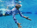 Person swimming underwater in a pool wearing pajamas - Learning Movement under water - Learn to Swim Program for Children in Singapore