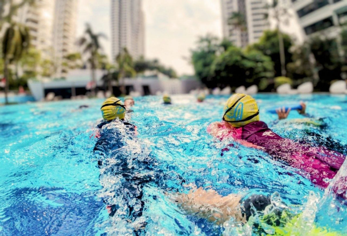 Children kicking across a condominium pool during a Dreamers swimming lesson Singapore