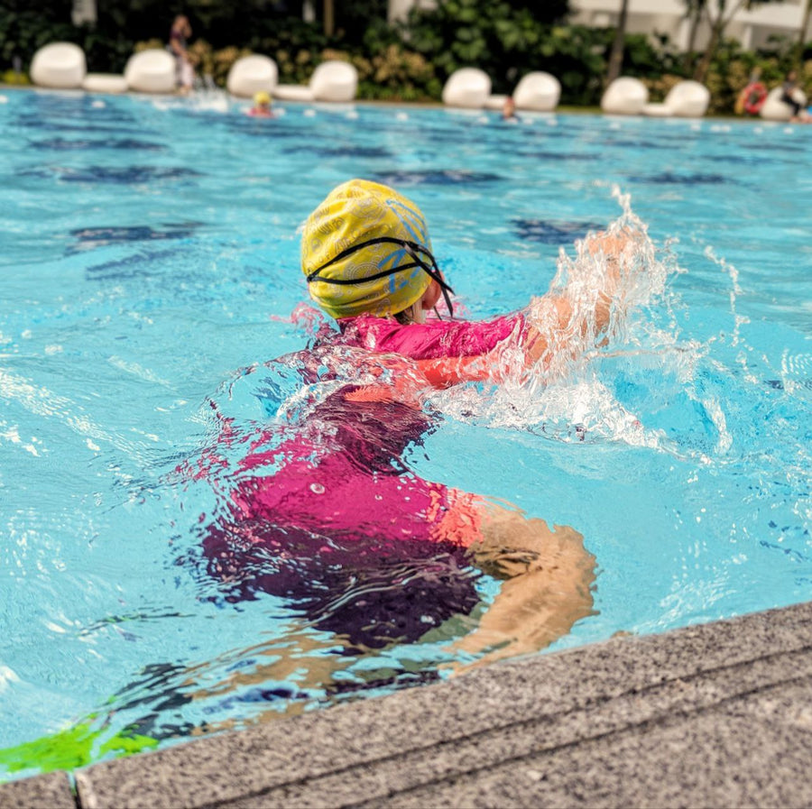 Young child practising a swim stroke in a condominium pool with Dreamers