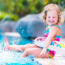 Toddler playing in a pool with water splashing around - Swimming Lessons for Toddler in Singapore