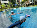Two swimmers in a pool with swim caps and arm floats - Private Swimming Lessons in Condominium Pool near Bukit Timah - Learn to Swim for Children