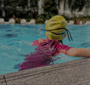 Young Child wearing a yellow swim cap and pink swimsuit in a pool - Condominium Swimming Lessons Singapore swim product