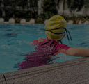 Young Child wearing a yellow swim cap and pink swimsuit in a pool - Condominium Swimming Lessons Singapore swim product