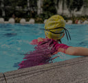 Young Child wearing a yellow swim cap and pink swimsuit in a pool - Condominium Swimming Lessons Singapore swim product